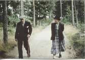 Två personer promenerar på en landsväg, 1960-tal. En okänd man med käpp samt Hilda Sandberg (1887-1973), 
