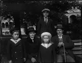 Kvinna, man och barn sitter och står vid en parkbänk, Uppsala