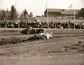 Moss passerar Bonniers bilvrak. Gelleråsen, Karlskoga. 1958-08-10