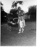Pojke skjutsar spädbarn i vagn i Ambernath, Indien, 1933