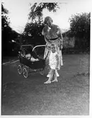 Pojke skjutsar spädbarn i vagn i Ambernath, Indien, 1933