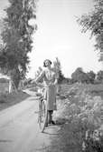 Kvinna med cykel på landsväg i Stora Mellösa, 1930-tal