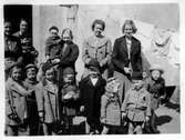 Grupp vid husvägg på Olaigatan, 1940-tal