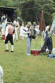 Barn och vuxna dansar kring stången vid midsommarfirande på Ekensås cirka 1982. En regnig aftor där spelmannen Frank Efraimsson spelar dragspel.