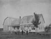 Familj framför hus, ca 1900