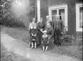 Grupporträtt, familjen uppställd framför husknuten.