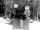 Grupporträtt, två kvinnor i vinterkläder och med muffar.