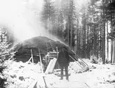 Porträtt, man stående framför en kolmila.