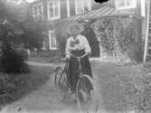 Porträtt, kvinna med cykel framför veranda.