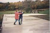 Labacka 1:3 1992-10-18. Karin Gustafsson och Lars Erik Andersson tar sig en svängom på den nygjutna grundplattan vid bygget av ladugården,