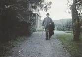 Robert Sandberg (1880-1961) spatserar med käpp på grusvägen utanför 