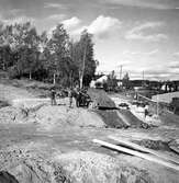 Första järnvägsbron mellan Viktoriagatan och Ådalsvägen under byggnad. Arnellsbacken går upp till vänster, Ådalsvägen rakt fram i bilden bakom lastbilen. 1930-tal.