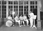 Jazzorkester med ynglingar som spelar i en lokal med stora spröjsade fönster (Societeten). Från vänster: trummor Evert Nilsson, banjo Valter Nilsson 