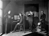 Okänd orkesterkvartett på en så trång scen att trumslagaren får stå på en tillbyggd liten avsats till höger. Övriga instrument är banjo, piano och fiol.
