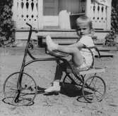 Flicka bakpå trehjuling, 1950-tal