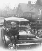 Pojke sitter på bil. 1960-tal