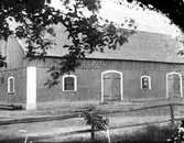 Ladugård, Marbogård (Jannes) i Sällstorp. Både fönster och dörrar har stickbågade öppningar och vitmålade omfattningar. Fasaden är putsad, men längs takfoten på på gavlarna sitter en träpanel.
(Negativet är skadat i höger sida)