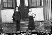 En ung man och en yngre flicka står på verandatrappan till småskolan i Sunbo, Sällstorp. (Bilden är skadad nedtill. Se även bild på ynglingen nr GEA033)