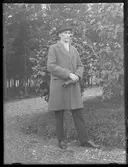 En man med hatt, rock och blanka skor.