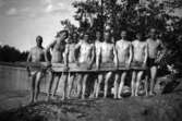 En grupp nakna män med en planka.