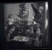 Fyra barn klär en julgran.