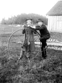 Två herrar och en höghjulig cykel.
