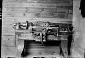 Svarv med gjutjärnsstativ från 1900-talets början som står vid en spåntad brädvägg. Tillverkare: W A Fell, Windermere.