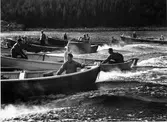 Skötrodden 1949, den sista i sitt slag. Båten längst fram styrs av Haldo Norberg. Båten nr 2 styrs av Einar Göransson, Betty Göransson i mitten och i fören sitter Gunnar Ekberg. Båten nr 3 stående Lars Erik Norberg. Båten nr 4 styrs av Albin Wedin. Båten nr 5 styrs av Ola Lundgren med Ingemar Wedin i ett barn som passagerare.  Båtarna befinner sig i höjd med den s.k. piksten och i samtliga båtar kommer man att vrida om bränslekranen från bensin- till fotogendrift. Man kan se den delade tanken i Haldo Norbergs båt.