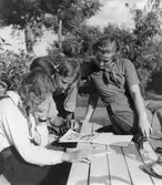 Ungdomar sitter vid en uteplats och tittar i ett teckningsblock.