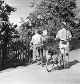 Cyklister, två unga män, utanför grinden till ett vandrarhem.