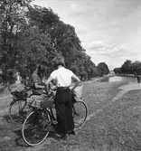 Cyklister, kvinna och man, med packning på pakethållarna står vid Göta kanal.