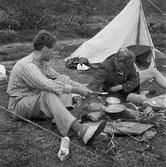 Dag Hammarskjöld och Sverker Åström på fjällvandring på Sulitelma. Två män har slagit läger och rest tält. Nu lagar de mat över eld.