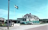 Kiosk vid Skummeslövsstrand med vajande flagga. Villa och bilar i bakgrunden.