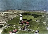 Flygbild över Morups Tånge fyr och bebyggelsen intill fyren med bostadshus, ekonomibyggnader och uthus. Stengärdesgårdar hägnar fyrområdet och man ser strandängarna ner mot havet.
Bild 1 är kolorerad och bilderna 2-3 är svartvita.