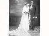 Brudparet herr och fru Otto Svensson från Valinge. Bruden har lång slöja som breder ut sig på golvet och en rosenbukett. Brudgummen bär frack.