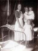 Sjuksyster med assistent och ett par skrofulösa barnpatienter står vid en säng på Kustsanatoriet Apelviken.