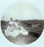Runt motiv på beskuret vykort. Sex unga kvinnor samlade ute i gräset vid Kustsanatoriet Apelviken. I bakgrunden ligger en ko. Troligen är de personal vid sanatoriet.