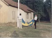 Staffan Bjerrhede och Berny Gustafsson hissar flaggan inför hembygdsgårdens midsommarfirande 1993. Hembygdsgården Långåker 1:3 ligger till vänster (ej i bild) och i bakgrunden ses Långåker 1:2 