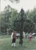 Midsommarfirande vid Hembygdsgården Långåker 1:3 1993. 
Staffan Bjerrhede, klädd i folkdräkt, står vid midsommarstången.
Relaterade motiv: A03389 - A03408.
