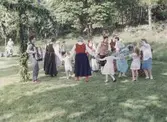 Midsommarfirande vid Hembygdsgården Långåker 1:3 1993. 
I mitten ses Staffan Bjerrhede klädd i folkdräkt. Den manlige okände dragspelaren är från Göteborg. Övriga namnuppgifter saknas.
Relaterade motiv: A03389 - A03408.