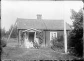 Män och kvinna utanför bostadshuset, Östhammar, Uppland