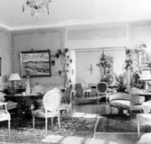 Interiörbild av salonger i överläkarvillan på Kustsanatoriet Apelviken från Albert Ahlbergs tid (1941-1966). Villan stod klar 1929 och överläkare Robert Hanson med familj var de första att flytta in. Den främre salongen har diskret målade väggfält och dörröverstycket pryds av en grisaillemålning (olika grå nyanser) med ett solur.