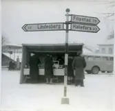 Västmanland.
Folkmarknad. Torgstånd och vägskylt.