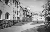 Vykort med vy längs fasaden av Spenshults sanatorium från 1913, ritat av arkitekt Ivar Tengbom. Arkitekturen innehåller såväl nationalromantiska som klassicerande drag. Tunga, valmade tak och den framträdande naturstenssockeln hör till det förra och det tresidiga gavelfältet samt den grunda så kallade rusticeringen av bottenvåningen liksom hörnkedjorna till det senare. (All text på vykortet har maskerats bort)