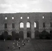Besökare på Borgholms slottsruin. De är på inre borggården, omgivna av det brunna slottets murar.