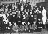 Porträtt av elever och fröknar vid Gävle Stads Arbetsstuga för barn Nr 2, på Södra Kungsgatan 31 i Gävle. Arbetsstugor inrättades för att håll främst fattigare barn sysselsatta med nyttigt arbete efter skoldagens slut. Foto från mars 1921.