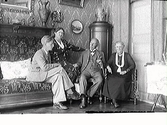 Fyra personer sitter i hörnet av fotograf Mathilda Ranchs salong. Uno Ranch och hans mor Agnes sitter i en stor jugendsoffa medan syskonen Wilhelm och Mathilda Ranch sitter på stolar.