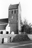 Båstad kyrka med kyrkogårdsmuren i förgrunden. Kyrkan är uppförd av tegel under 1400-talets förra hälft.