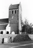 Båstad kyrka med kyrkogårdsmuren i förgrunden. Kyrkan är uppförd av tegel under 1400-talets förra hälft.