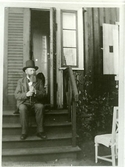 Författaren, folklivsskildraren och läkaren August Bondeson sitter på trappan till sitt lantställe på 
